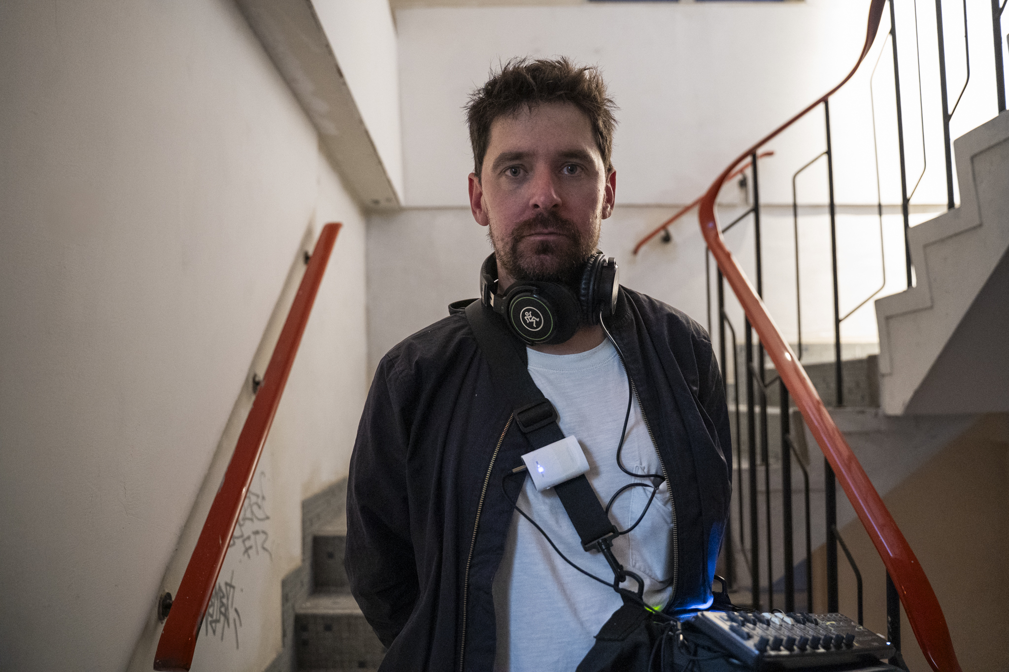 man, Tim Shaw, with dark hair covering standing in a stairwell after an Ambulation Soundwalk